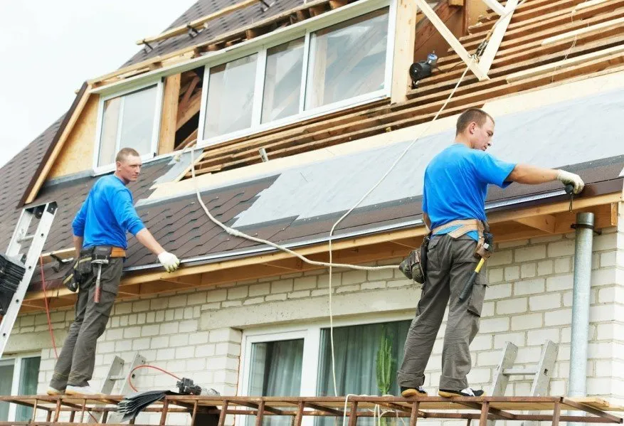2 workers with blue shirts installing a roof